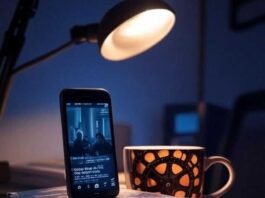 Cinematic Videos on Your Phone? Discover the Best Mobile Apps! Alt text: A cluttered desk in a dimly lit Brooklyn apartment with an iPhone propped on books, displaying a cinematic video, a shaky hand suggesting excitement, and a quirky film reel coffee mug glowing in warm amber light from a desk lamp, with a faint lens flare and moody indigo shadows.